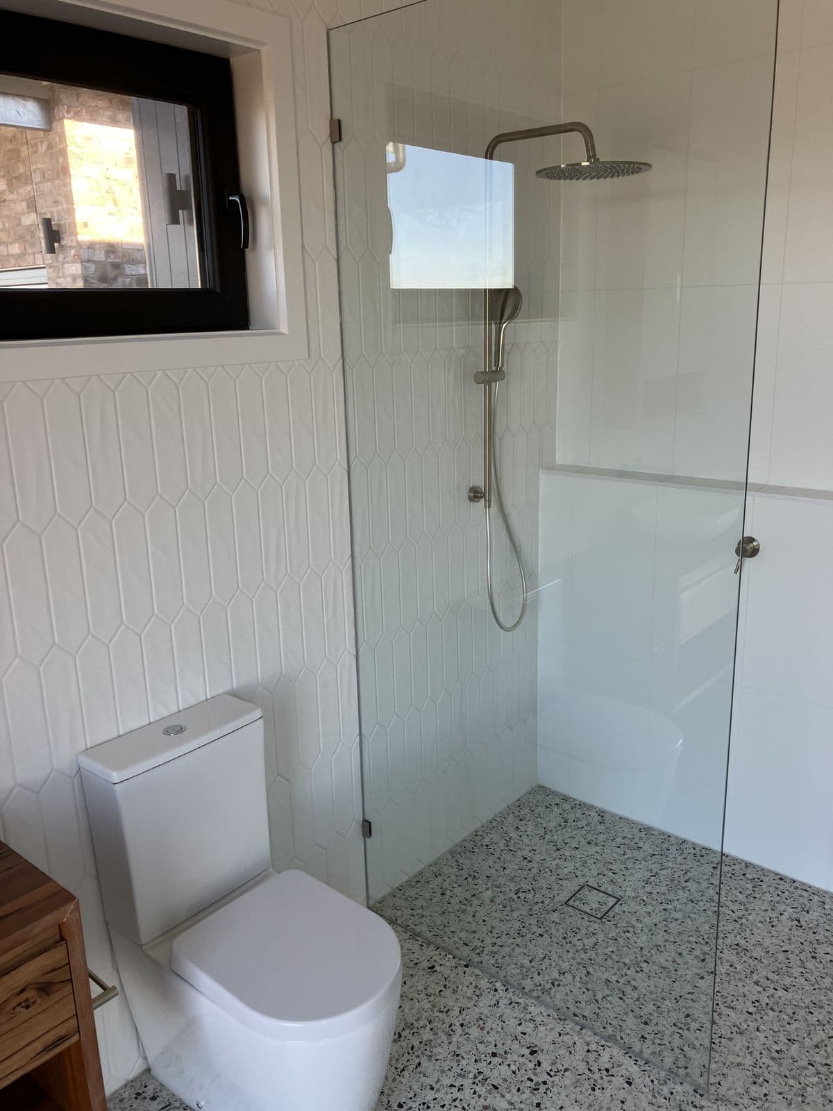 Walk-in shower and toilet with terrazzo floor in a freshly painted bathroom