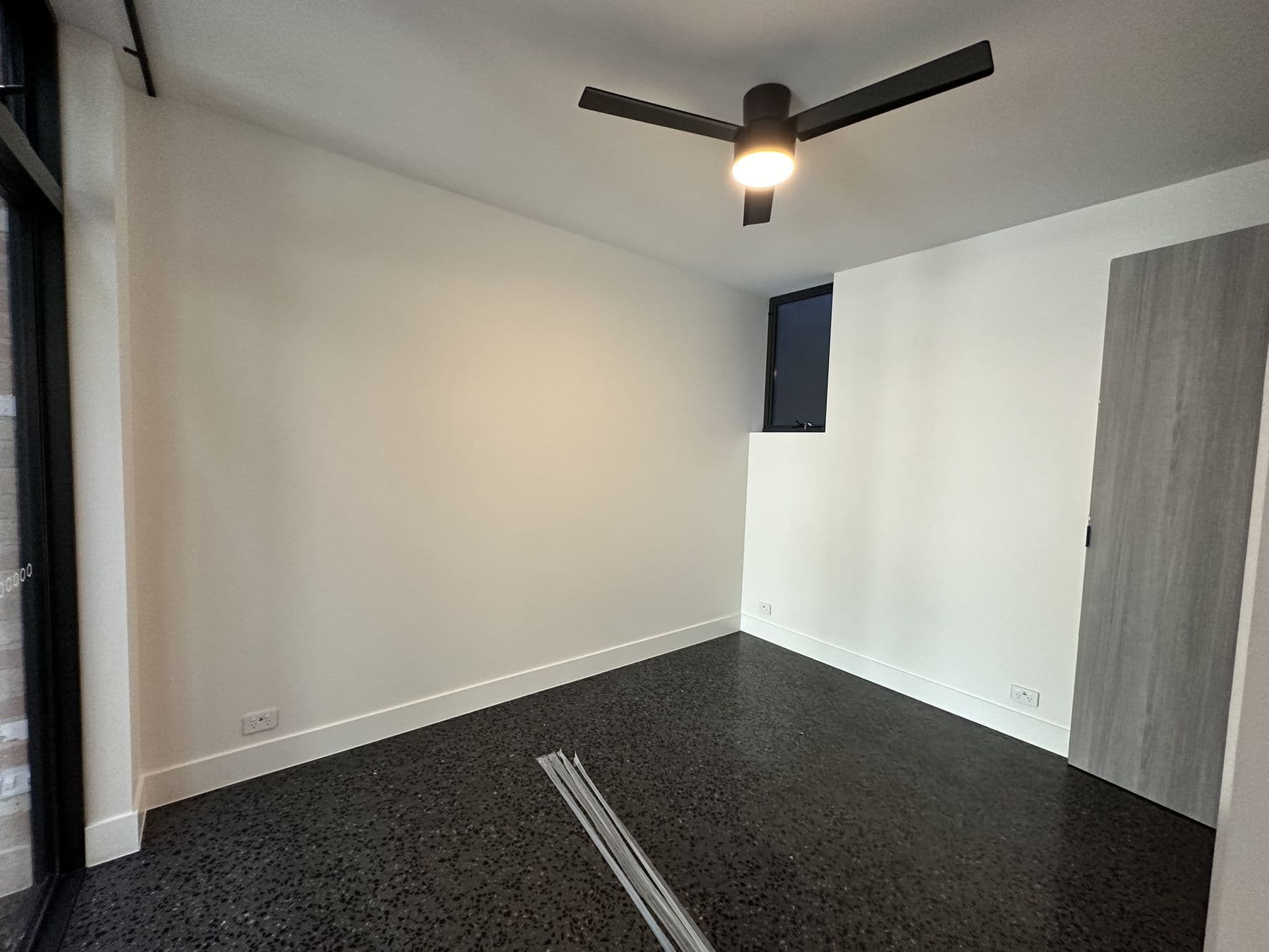 Crisp white room with dark polished floor and a ceiling fan — freshly painted